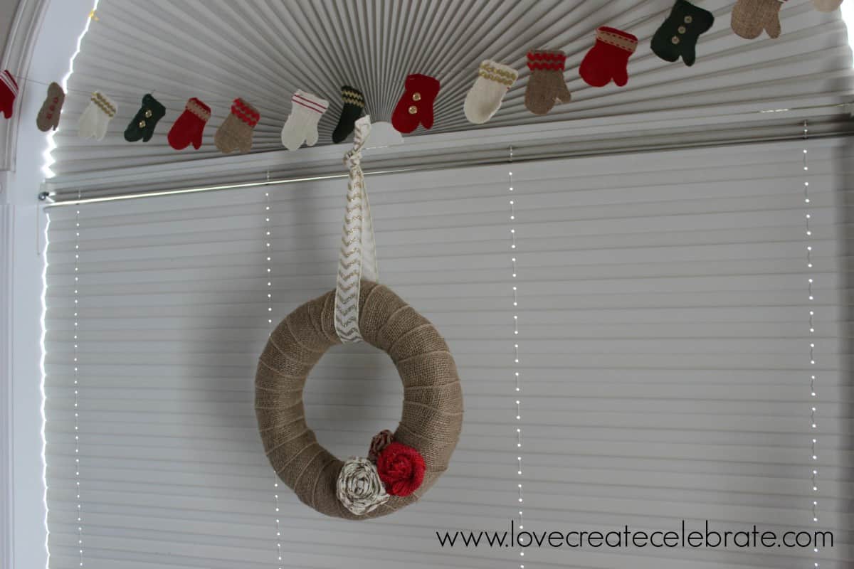 Burlap wreath with a burlap mitten garland above really add to the burlap Christmas decoration theme