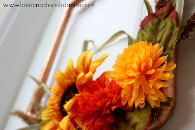 Close up of the artificial flowers on the DIY copper pipe fall wreath.