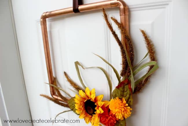 DIY copper pipe fall wreath hanging on a door.