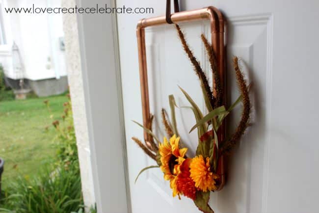 DIY copper pipe fall wreath on an outer door.