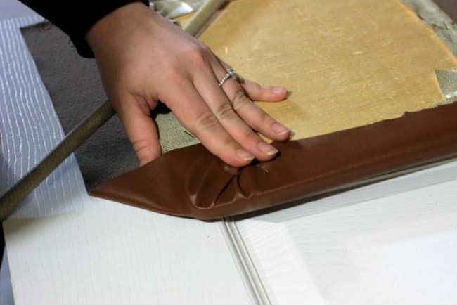 Work one side at a time, folding up and stapling the faux leather in place along the bottom of the cushion