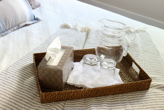 Pitcher and glasses on a wicker tray in the cozy guest room.
