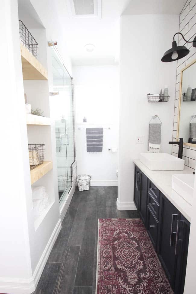 A beautiful modern bathroom renovation with chrome and matte black faucets, sleek modern fixtures and natural wood accents. Beautiful transformation!