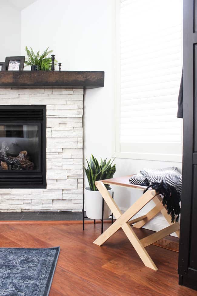 A beautiful Modern Master Bedroom Renovation Reveal! Gorgeous bold wallpaper, black, white and grey tones alongside wooden accent furniture. Ikea cabinets with a sliding barn door. And a white brick fireplace with a dark wooden mantel. Touches of blue and deep red finish the space perfectly. Beautiful transformation! 