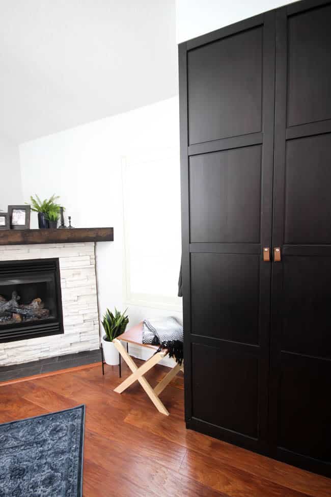 A beautiful Modern Master Bedroom Renovation Reveal! Gorgeous bold wallpaper, black, white and grey tones alongside wooden accent furniture. Ikea cabinets with a sliding barn door. And a white brick fireplace with a dark wooden mantel. Touches of blue and deep red finish the space perfectly. Beautiful transformation! 