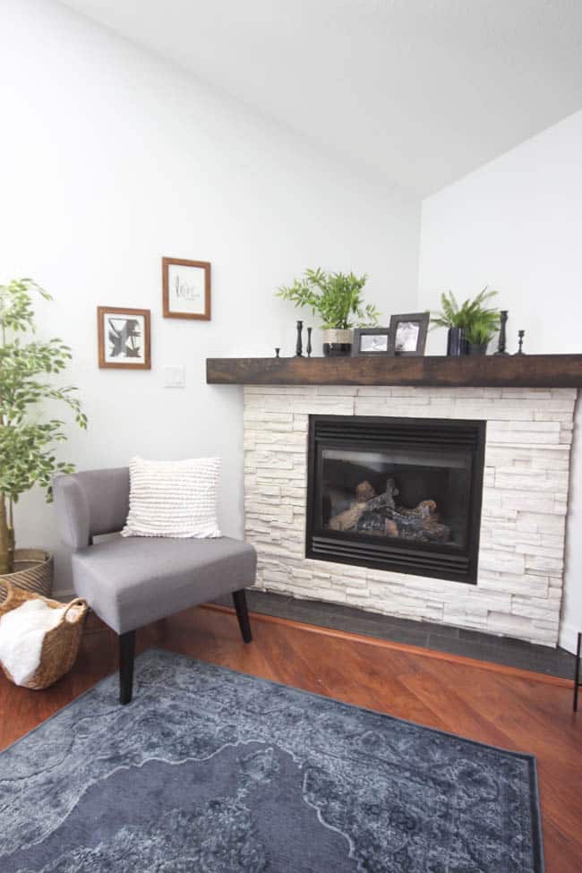 A beautiful Modern Master Bedroom Renovation Reveal! Gorgeous bold wallpaper, black, white and grey tones alongside wooden accent furniture. Ikea cabinets with a sliding barn door. And a white brick fireplace with a dark wooden mantel. Touches of blue and deep red finish the space perfectly. Beautiful transformation! 