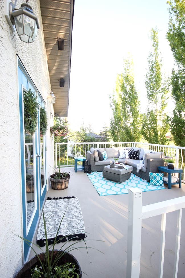 A stunning backyard makeover inspired completed with Behr paints. Love the bright painted blue doors, and the grey outdoor sectional. Beautiful DIY pallet side tables, and black and white accessories complete the space. Summer is here! 