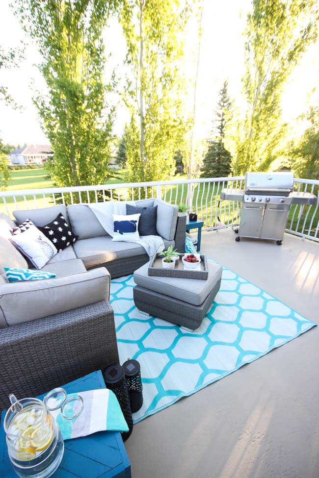 A stunning backyard makeover inspired completed with Behr paints. Love the bright painted blue doors, and the grey outdoor sectional. Beautiful DIY pallet side tables, and black and white accessories complete the space. Summer is here! 