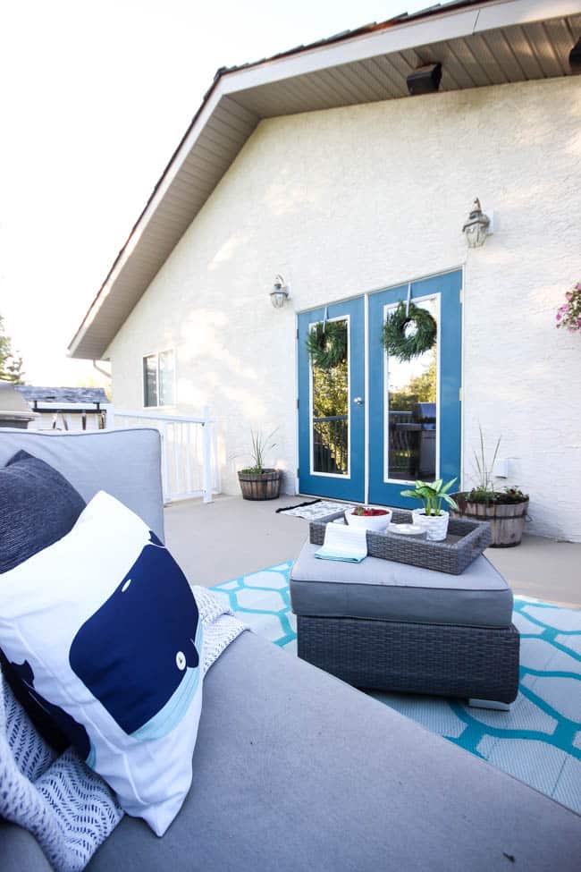 A stunning backyard makeover inspired completed with Behr paints. Love the bright painted blue doors, and the grey outdoor sectional. Beautiful DIY pallet side tables, and black and white accessories complete the space. Summer is here! 