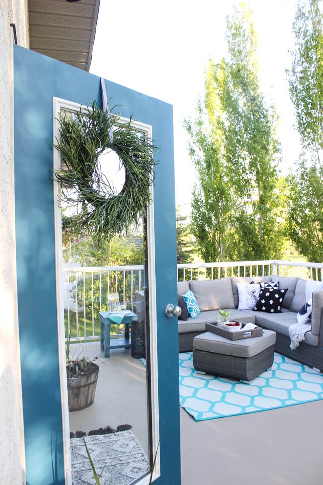 A stunning backyard makeover inspired completed with Behr paints. Love the bright painted blue doors, and the grey outdoor sectional. Beautiful DIY pallet side tables, and black and white accessories complete the space. Summer is here! 