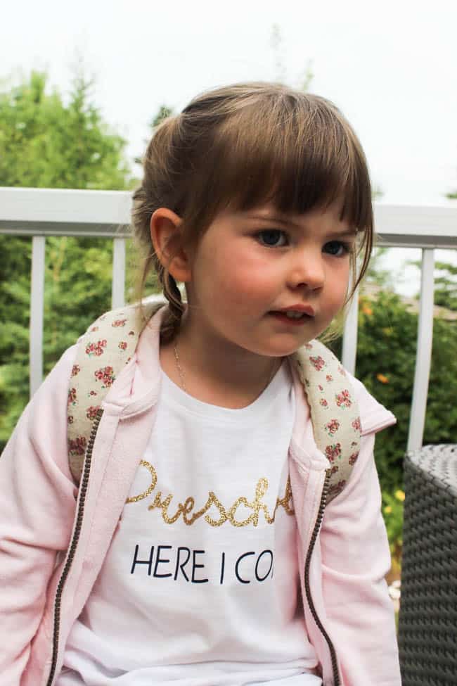 Little girl wearing first day of school outfit with custom shirt with text "Preschool here I come" 