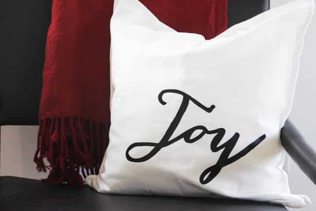 White pillow with "Joy" heat transferred on for the easiest ever Christmas pillows
