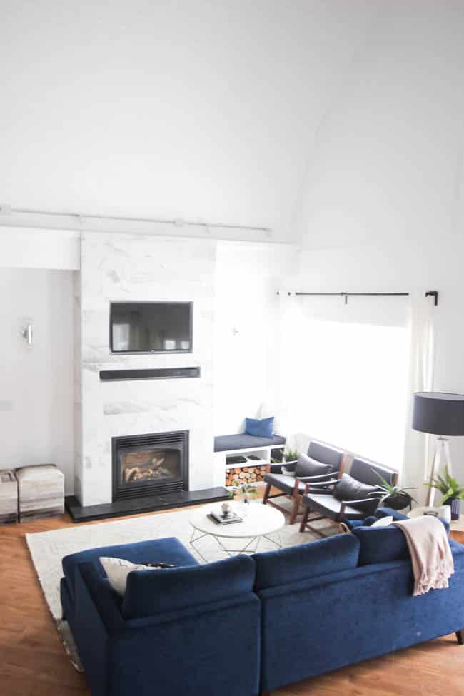 This gorgeous Modern Living Room reveal is finally here! This space came a long way from an outdated, empty space in this beautiful barn home. Love all of the contemporary DIY and decor ideas in this beautiful living space! The tiled fireplace and blue couch are stunning!