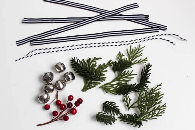 The supplies you need for these mini wreath ornaments are some mini silver bells, juniper leaves, ribbon, and some holly berries. 