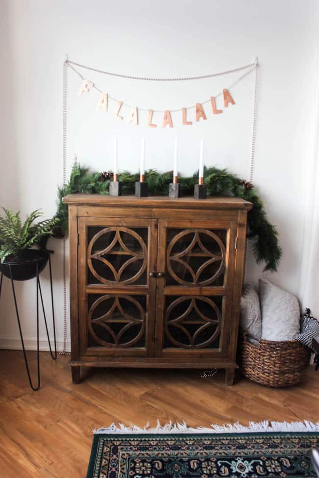 Wooden sideboard decorated with greenery and candles for the Christmas dining room 