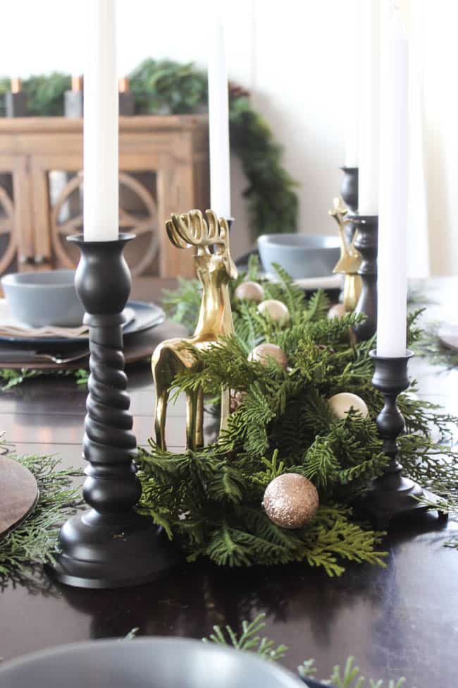 Centrepiece with greenery stems and gold and black accents on the table in the Christmas dining room 