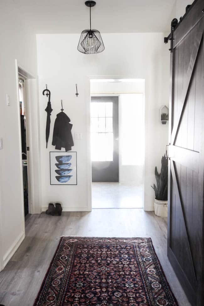 Beautiful hallway decor ideas! Love the eclectic mix of materials and styles in this space. Beautiful light flooring, gorgeous overlapping barn doors, modern artwork, and a vintage hallway runner complete the space. Perfect ideas to fill up a wide hallway!