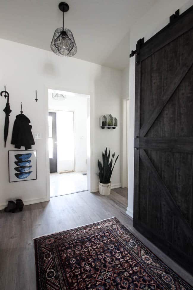 Beautiful hallway decor ideas! Love the eclectic mix of materials and styles in this space. Beautiful light flooring, gorgeous overlapping barn doors, modern artwork, and a vintage hallway runner complete the space. Perfect ideas to fill up a wide hallway!