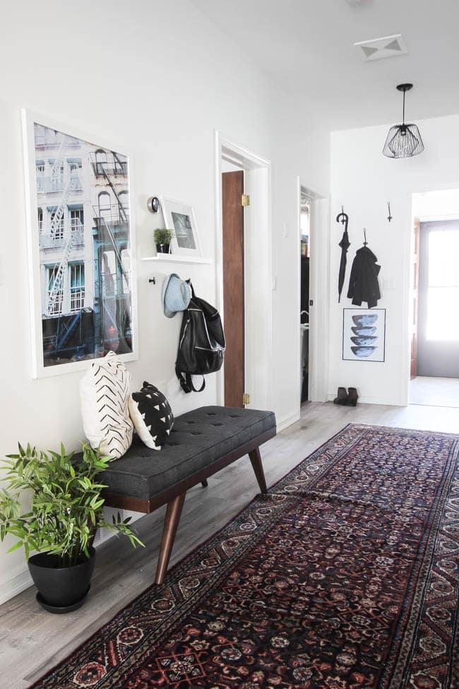 Beautiful hallway decor ideas! Love the eclectic mix of materials and styles in this space. Beautiful light flooring, gorgeous overlapping barn doors, modern artwork, and a vintage hallway runner complete the space. Perfect ideas to fill up a wide hallway!