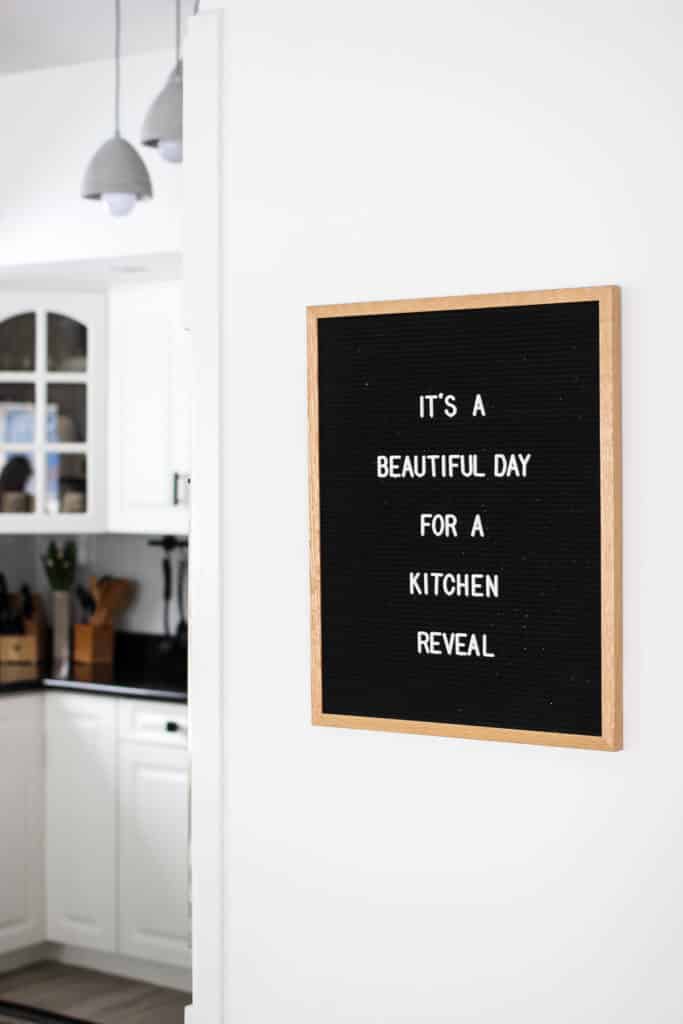 Wow! This stunning modern kitchen was transformed in just one weekend! Love the design ideas in this stunning black and white kitchen! The kitchen features white cabinets, black countertops, black hardware, matte black faucet, black sink, and wood accents. The use of countertop paint and peel and stick tile was brilliant! 