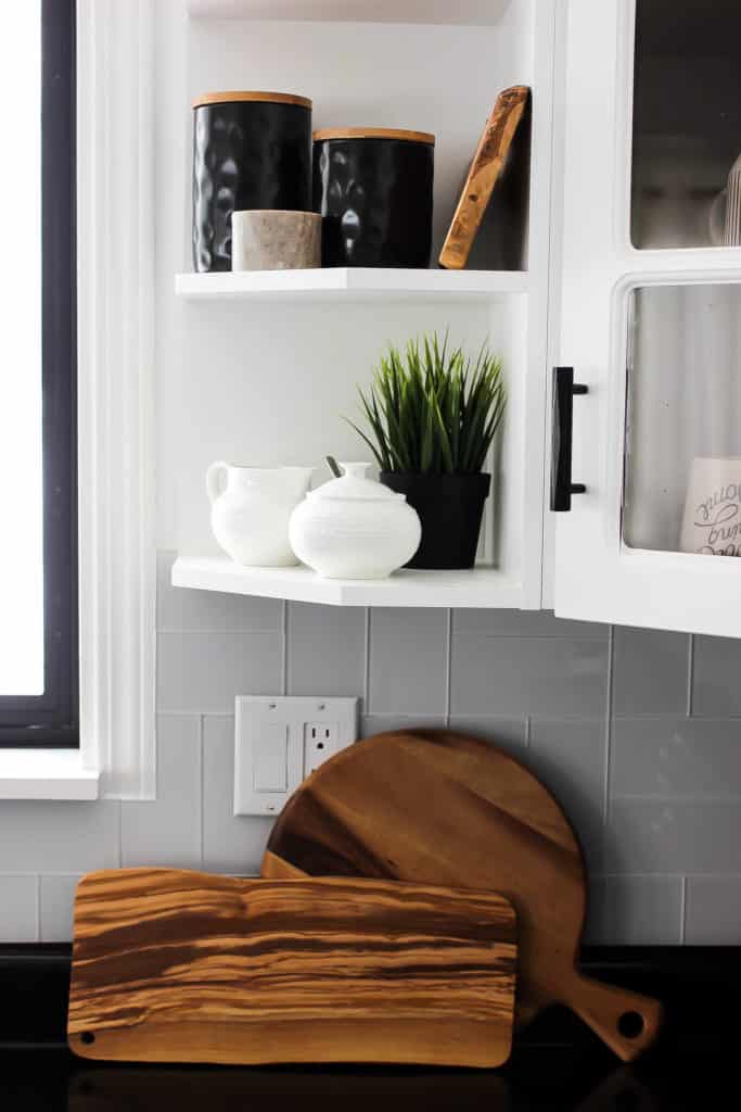 Wow! This stunning modern kitchen was transformed in just one weekend! Love the design ideas in this stunning black and white kitchen! The kitchen features white cabinets, black countertops, black hardware, matte black faucet, black sink, and wood accents. The use of countertop paint and peel and stick tile was brilliant!