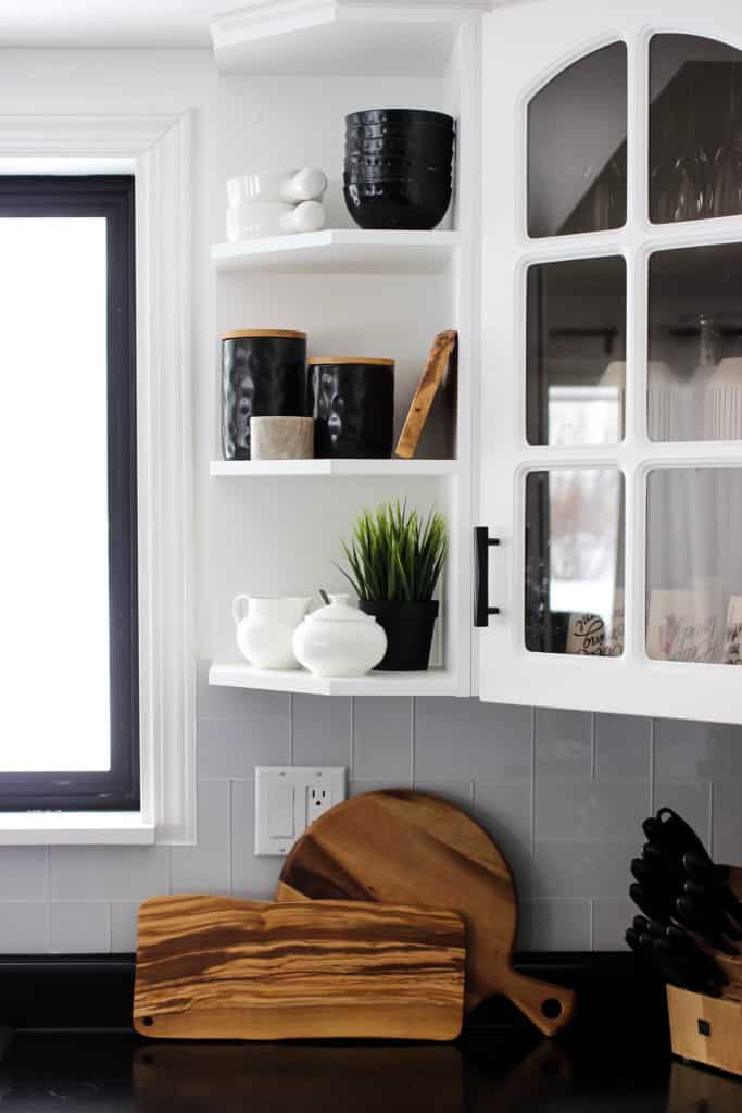 Wow! This stunning modern kitchen was transformed in just one weekend! Love the design ideas in this stunning black and white kitchen! The kitchen features white cabinets, black countertops, black hardware, matte black faucet, black sink, and wood accents. The use of countertop paint and peel and stick tile was brilliant! 