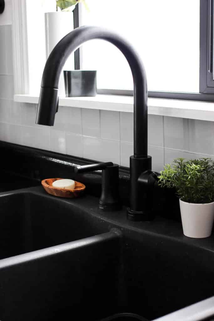 Wow! This stunning modern kitchen was transformed in just one weekend! Love the design ideas in this stunning black and white kitchen! The kitchen features white cabinets, black countertops, black hardware, matte black faucet, black sink, and wood accents. The use of countertop paint and peel and stick tile was brilliant!