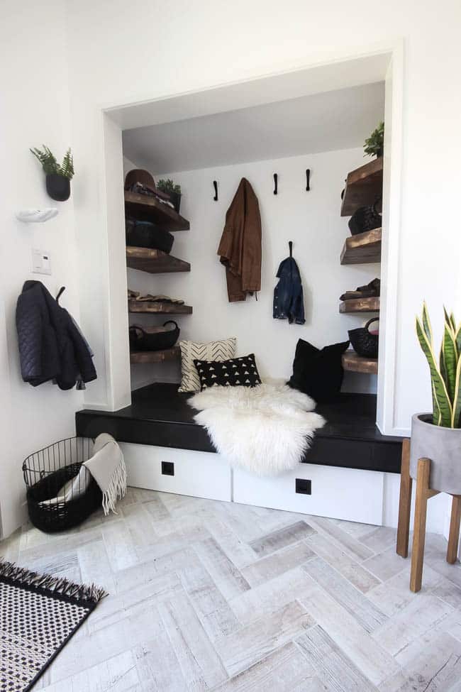 This gorgeous modern entryway reveal is here! What a huge transformation from the outdated space it once was! From the beautiful bench, to the herringbone floors, to the black front door, and the wood accent feature wall. This entry is stunning!