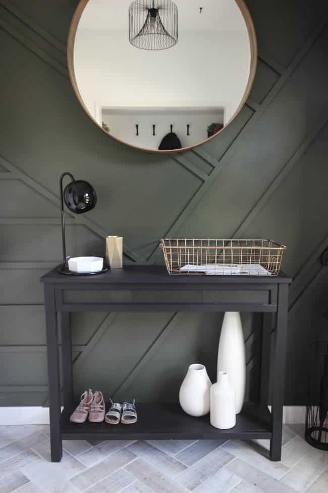 This gorgeous modern entryway reveal is here! What a huge transformation from the outdated space it once was! From the beautiful bench, to the herringbone floors, to the black front door, and the wood accent feature wall. This entry is stunning!