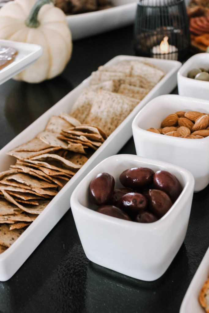 A wide assortment of crackers, nuts, olives, and fruits are essential for a fall themed appetizer spread