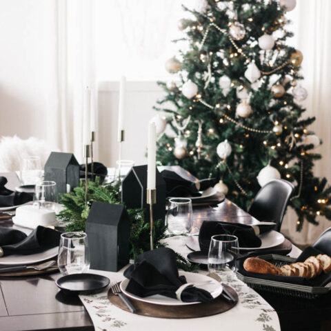 A stunning holiday tablescape and DIY table runner! This beautiful modern table setting was put together with a few affordable painted pieces creating a beautiful dark a moody Christmas table with greens, blacks, and whites. The eucalyptus stamped table runner is gorgeous! #tablescape #Christmas #darkandmoody #Holiday #blackandwhite #tablesetting