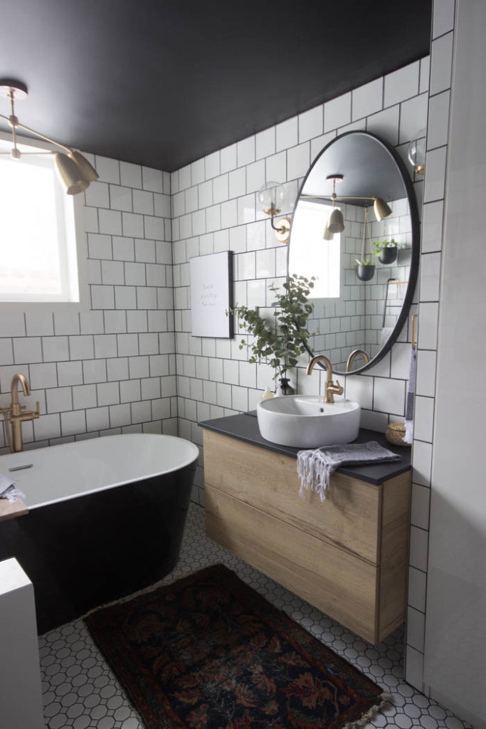 Wow! This modern Bathroom Reveal is absolutely stunning! What a gorgeous space! Everything from the black tub and shower frame, the champagne bronze faucets, and the wood vanity to the black ceiling and built-in storage units! What an incredible transformation! #modernbathroom #paintedceiling #blackceiling #blackandwhite #bathroom #remodel #renovations