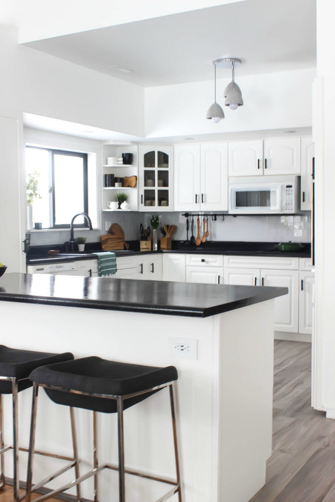 renovated kitchen with white cabinets and black countertops