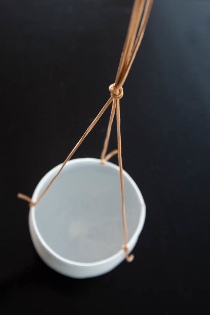 tying leather strings for a white flower pot