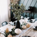 Thanksgiving tablescape with black plates, wood accents and gold cutlery