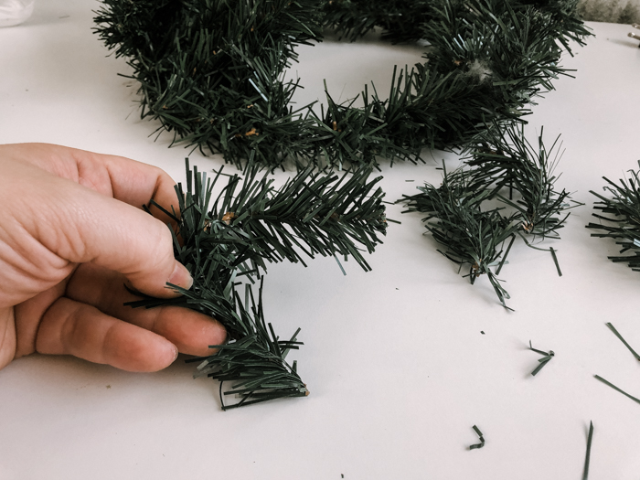 cutting branches of faux pine wreath