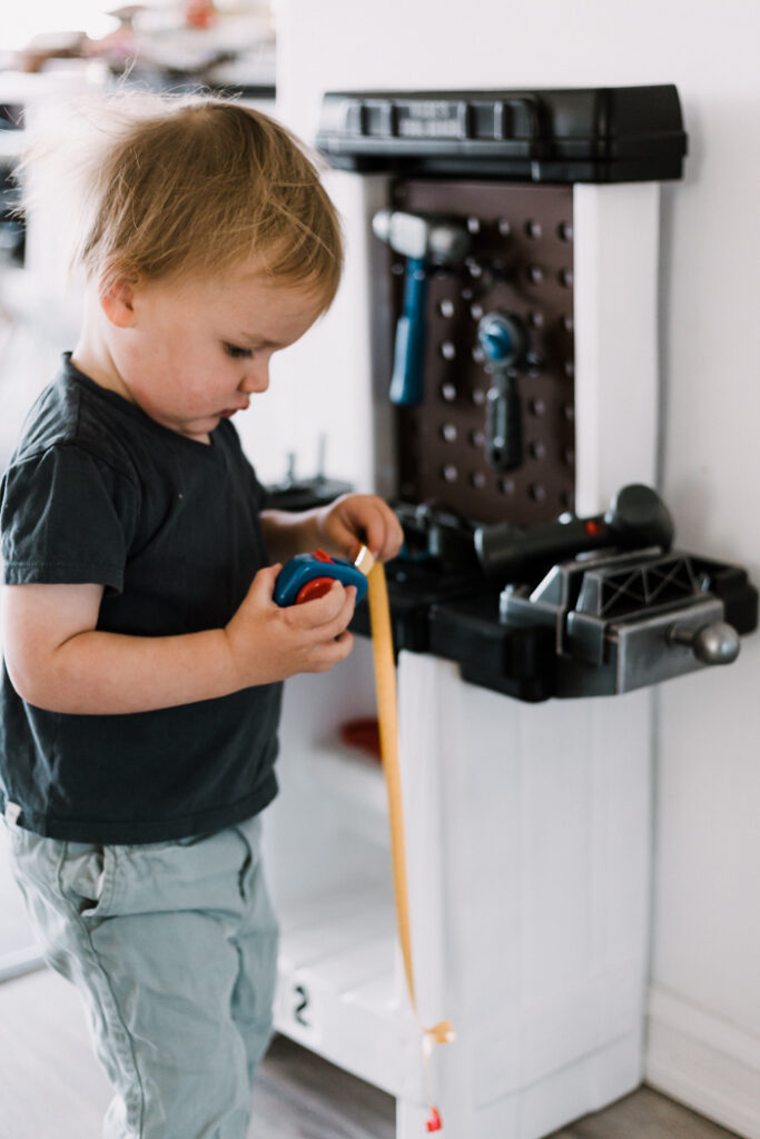 little boy playing with tool bench