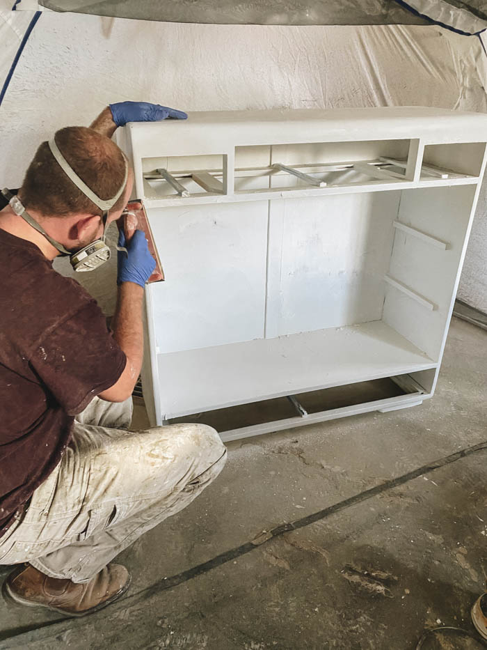 painting an old cabinet with a paint sprayer