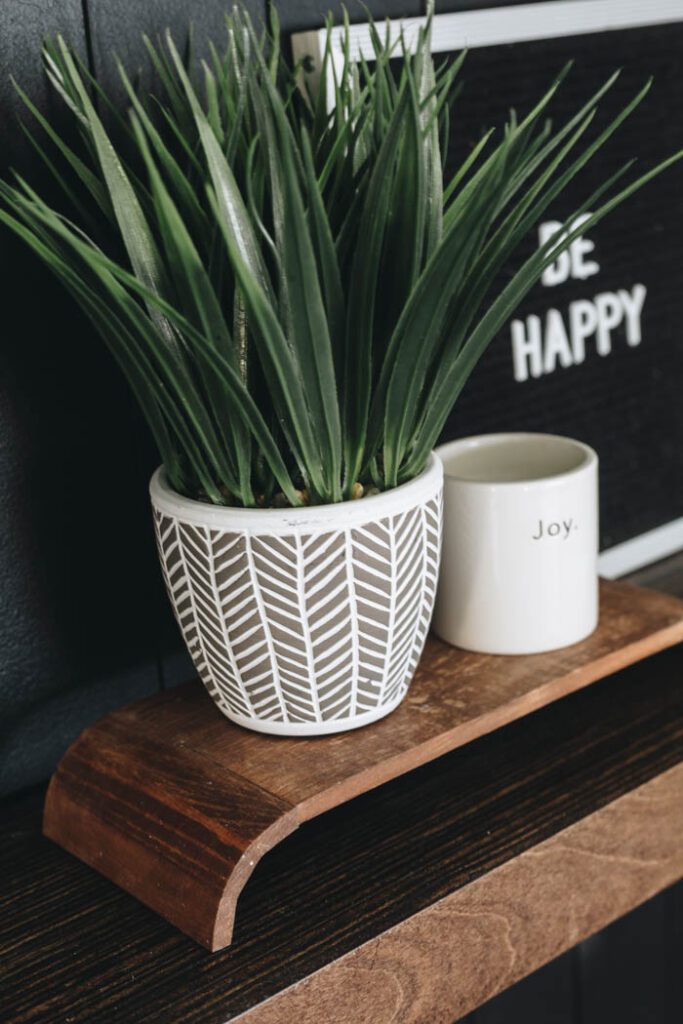 close up of modern wooden pedestal with plant and mug sitting on it