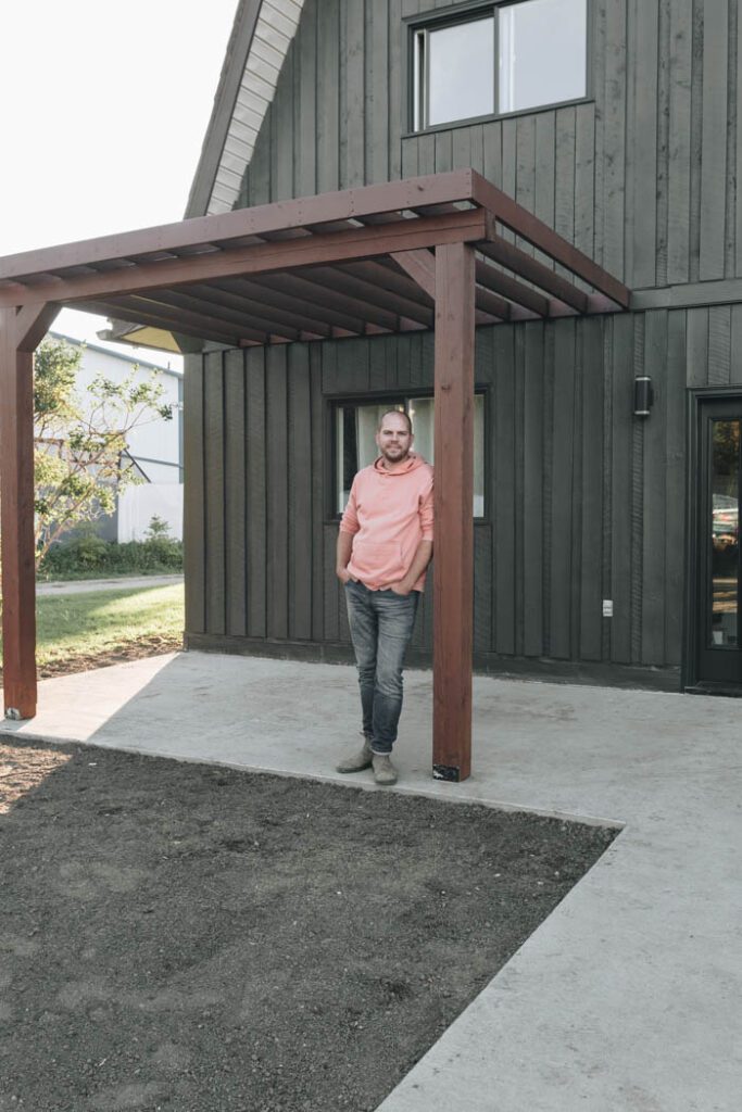 handsome man standing on new concrete pad and by pergola