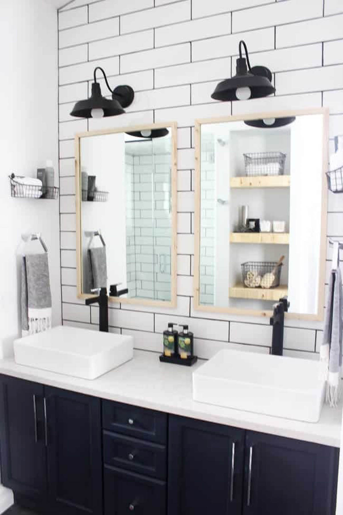 Renovated bathroom with wood-framed mirrors and subway tiles