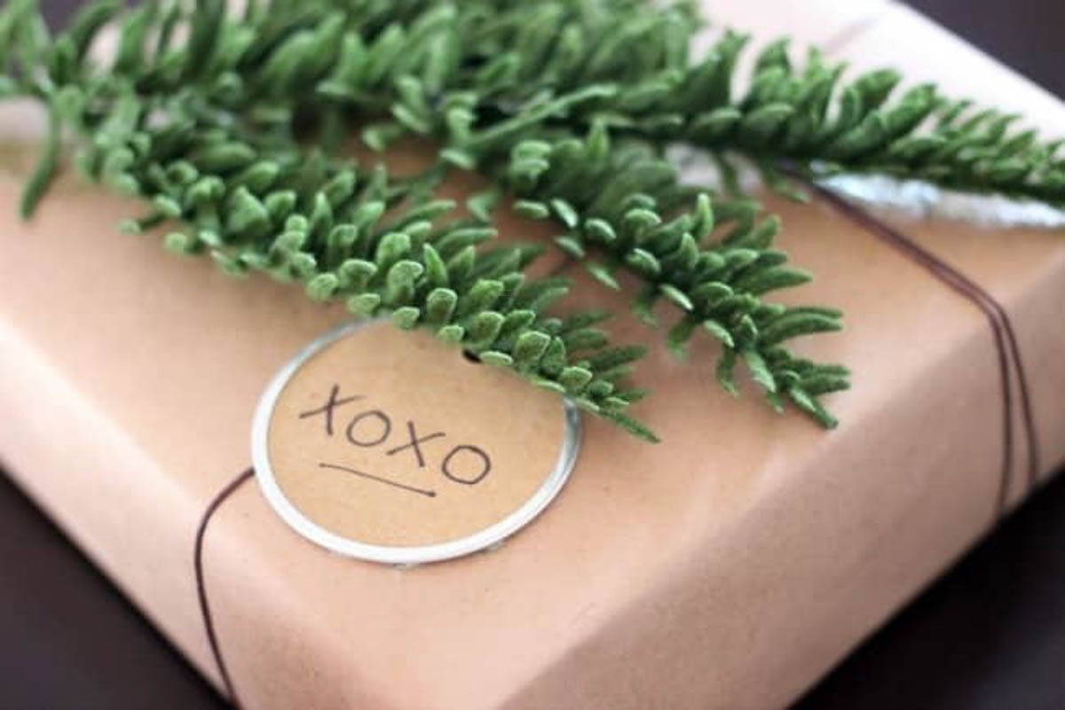Close up of brown rustic gift wrapped present with greenery and xoxo tag
