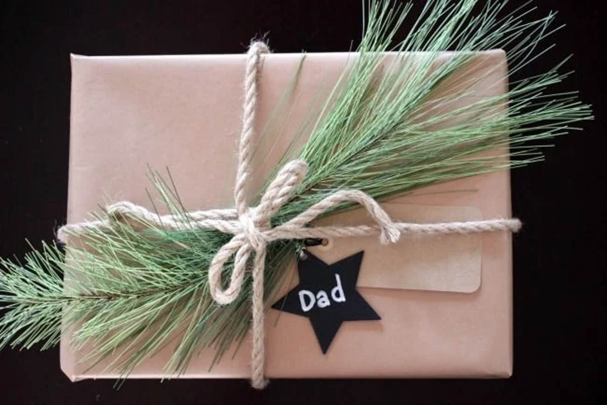 Rustic brown gift wrapped present with greenery star tag and rope bow
