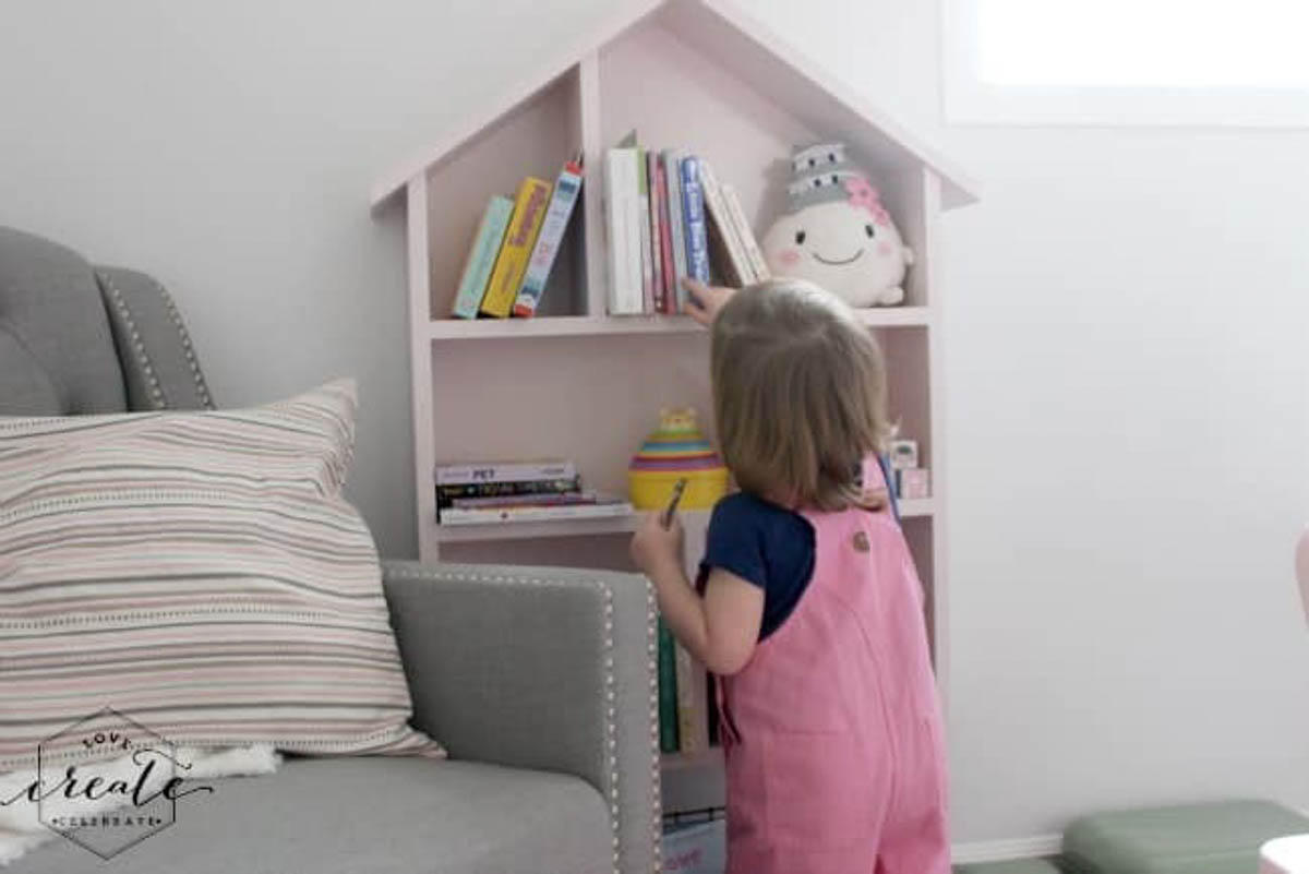 Girl picking out a book on the house bookshelf