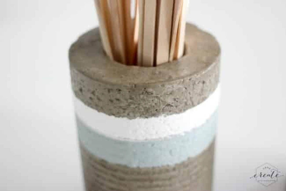 Close up of a painted concrete vase holding popsicle sticks