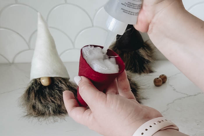 adding glue to hats for DIY fall gnomes