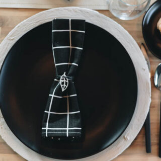 place setting with charger, black plate, and napkin with minimalist napkin ring