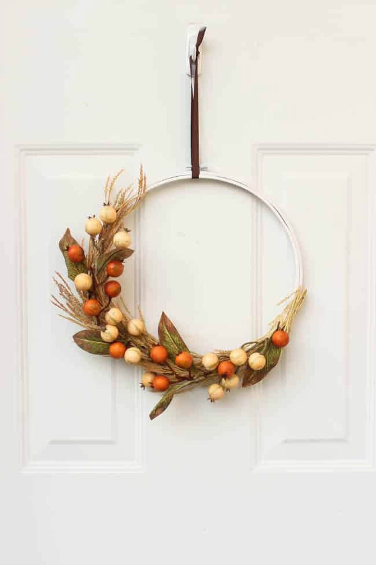 Completed autumn embroidery hoop wreath hanging on a door.