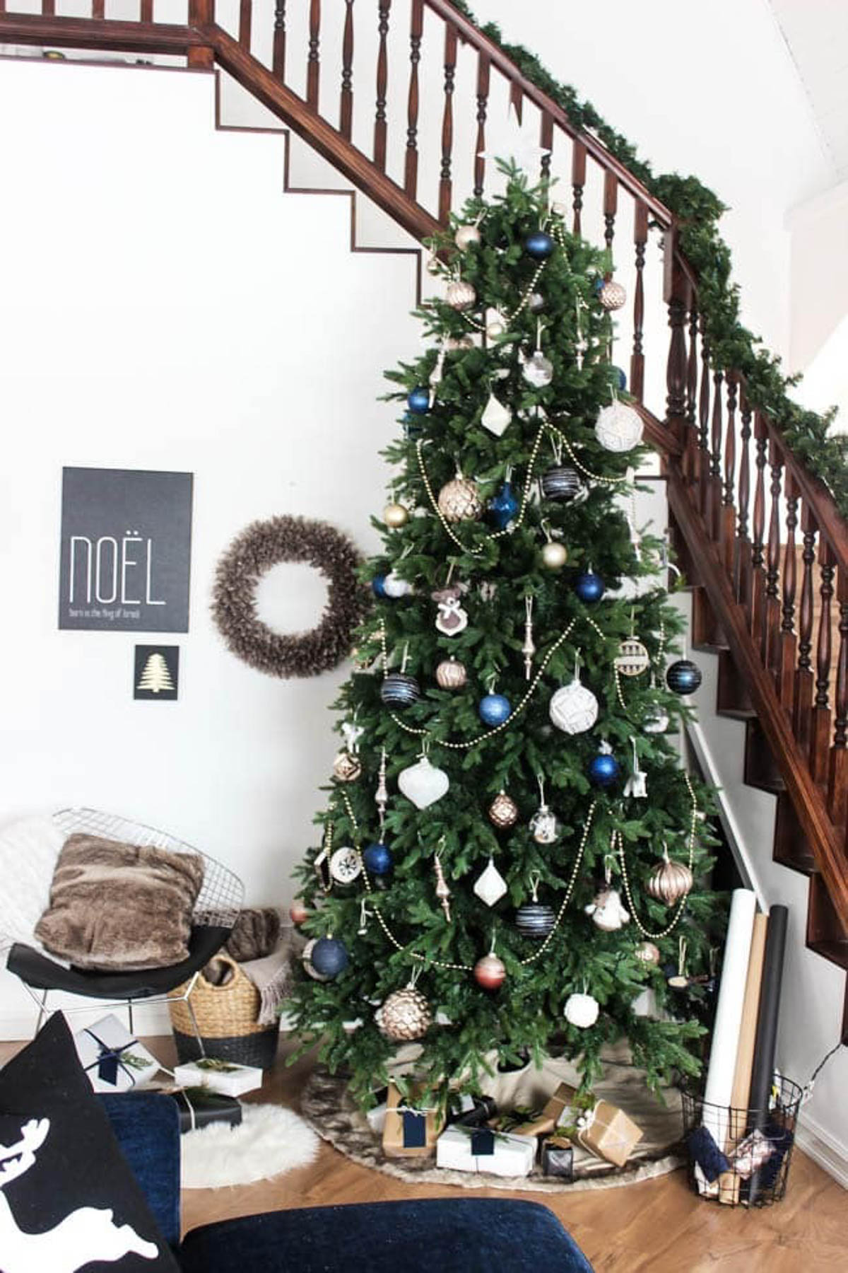 Decorated designer Christmas tree near a stairway.
