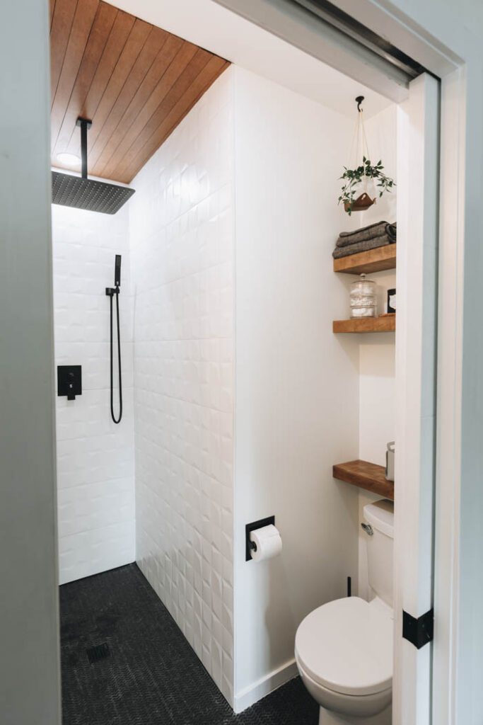 image of bathroom shower and toilet area with wood shelves